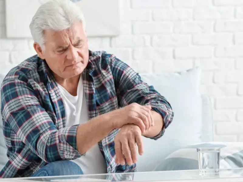 Older adult resting an unsteady hand on a table