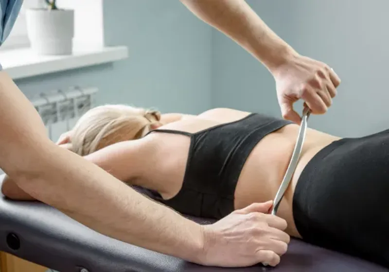 Doctor of Physical Therapy using a Graston instrument along a patient's calf