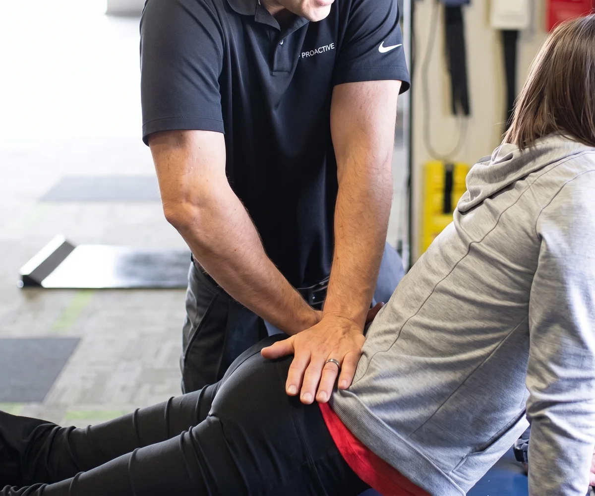 Physical therapist assisting a patient through a hands-on hip and back stretch